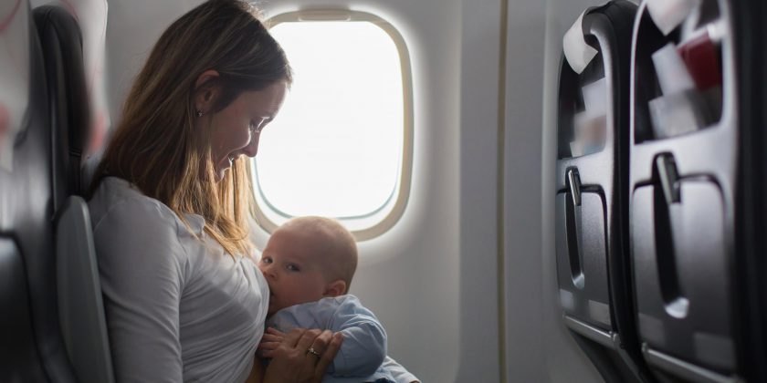 Mother breastfeeding her baby by an aeroplane window while travelling